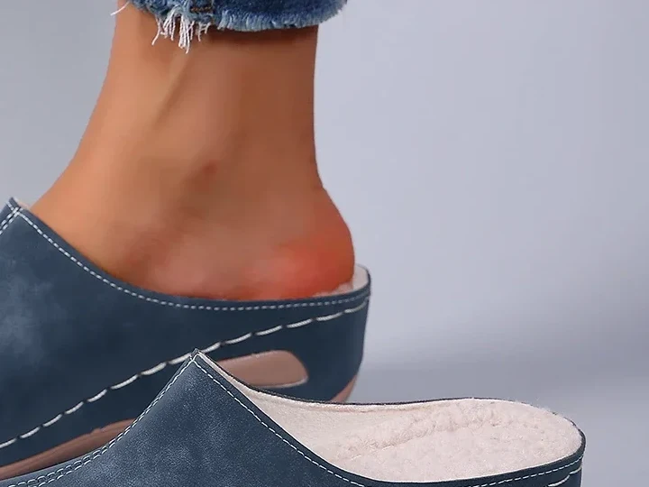 Il tallone appoggiato dentro la pantofola blu aperta dietro